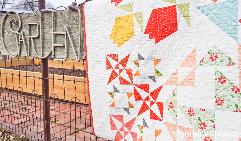 Bloom-Topia quilt draped on garden fence